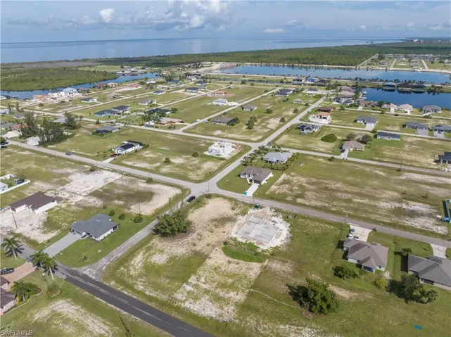 Aerial view of property and surrounding area featuring a nearby body of water and nearby suburban area