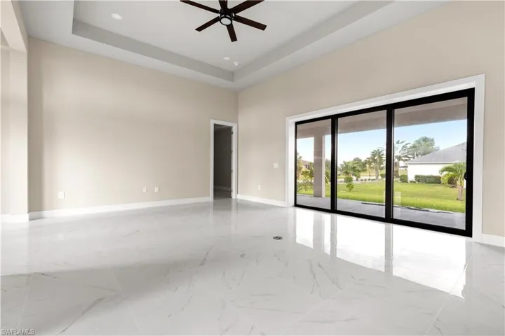 Unfurnished room with ceiling fan, light marble finish floors, recessed lighting, a high ceiling, and a raised ceiling