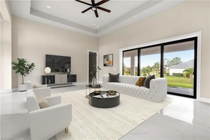 Living room featuring light marble finish flooring, a towering ceiling, a ceiling fan, recessed lighting, and a tray ceiling