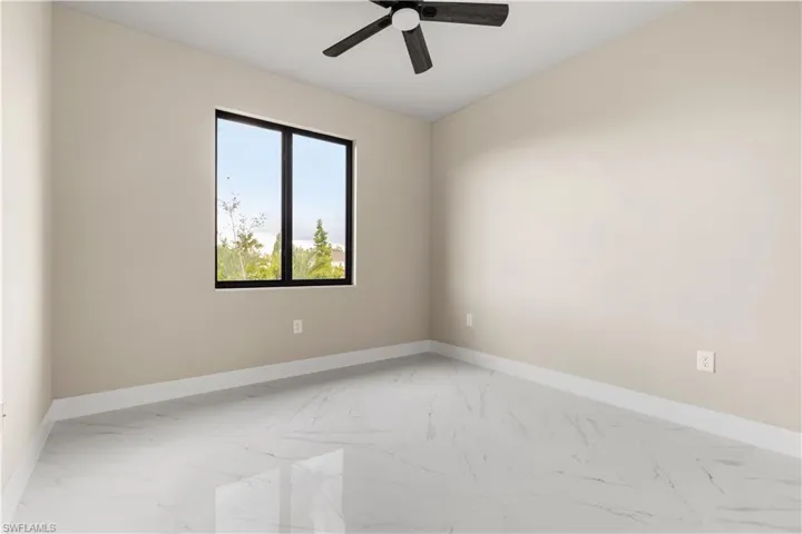 Empty room featuring light marble finish floors and a ceiling fan