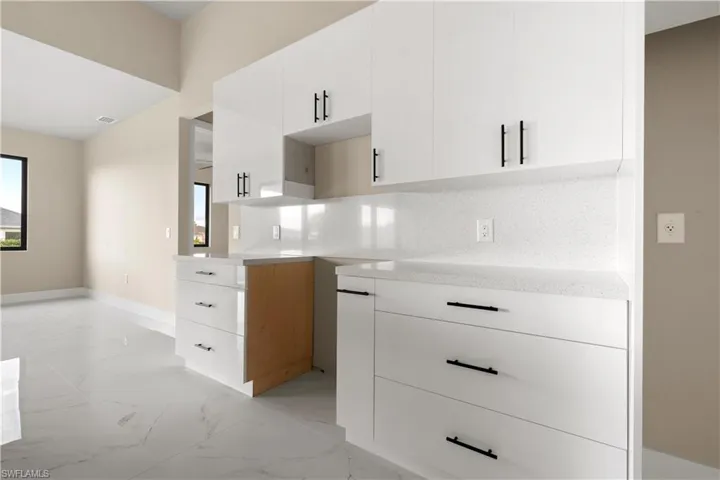 Kitchen with light marble finish flooring, decorative backsplash, white cabinets, and modern cabinets