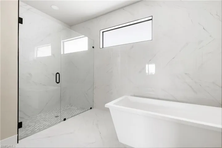 Bathroom with a soaking tub, marble tiled flooring, and a marble finish shower