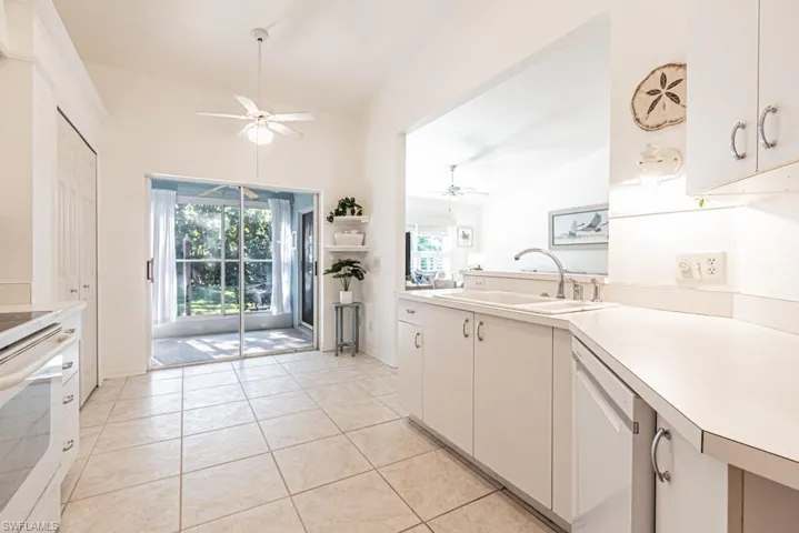 Kitchen featuring dishwasher, white cabinets, vaulted ceiling, and sink