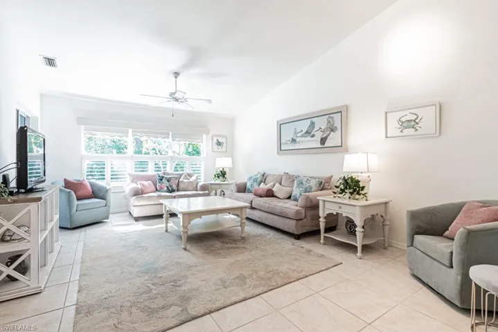 Living room featuring ceiling fan, light tile patterned floors, and lofted ceiling