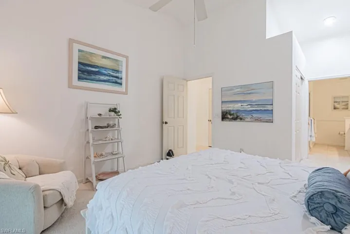 Carpeted bedroom with a high ceiling and ceiling fan