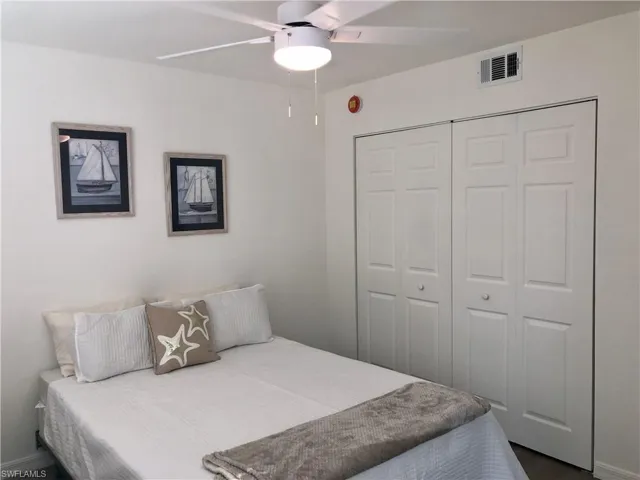 Interior room featuring a white ceiling fan with integrated lighting, a ceiling-mounted air vent, and bi-fold closet doors with panel detailing