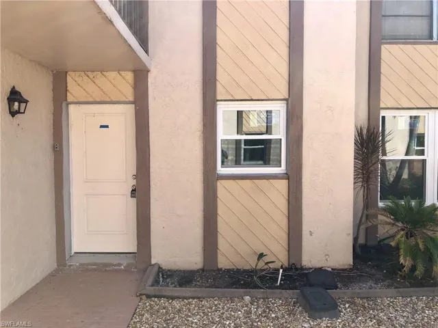 Exterior entryway featuring a paneled door, wall-mounted light fixture, and textured siding details