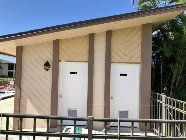 Exterior building featuring angled siding patterns, two white utility doors with metal grates, and a wall-mounted outdoor light fixture