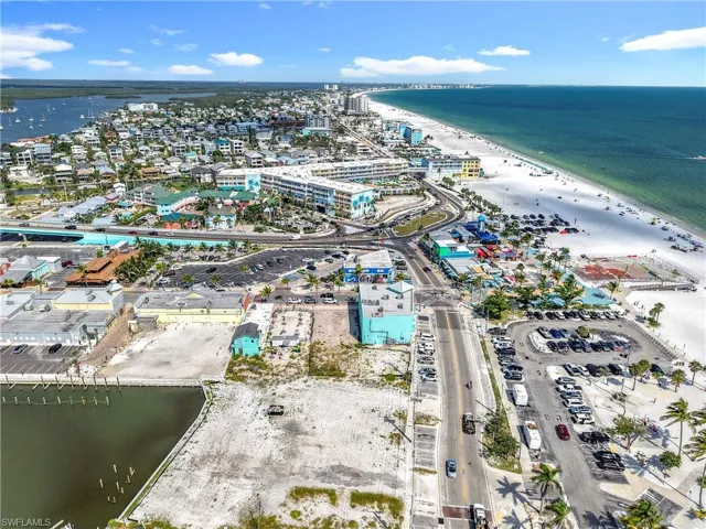 Aerial view of property and surrounding area featuring waterfront with a beach