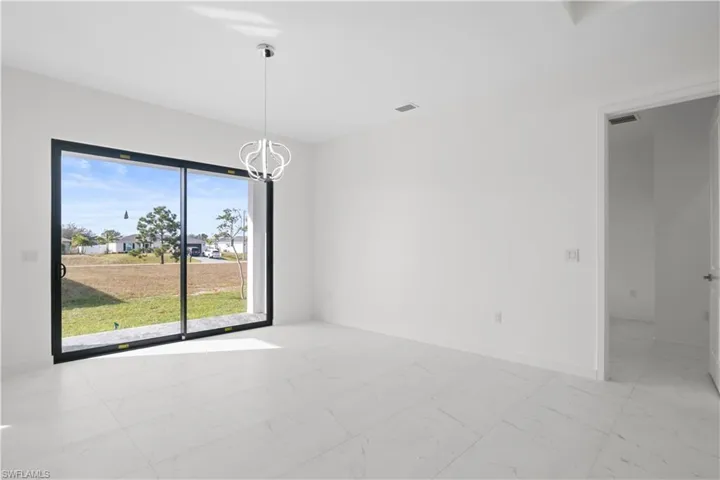 Unfurnished room featuring light marble finish floors and a chandelier