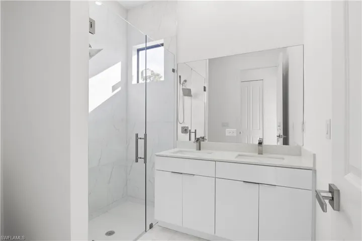 Bathroom with a marble finish shower and double vanity