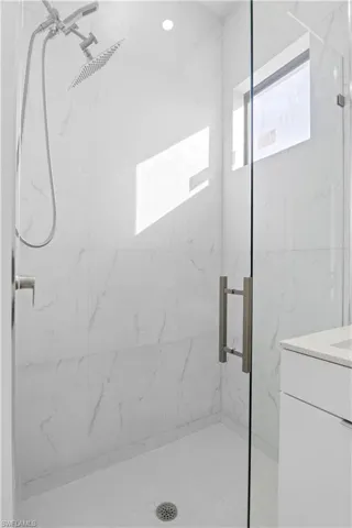 Full bathroom featuring a marble finish shower and vanity