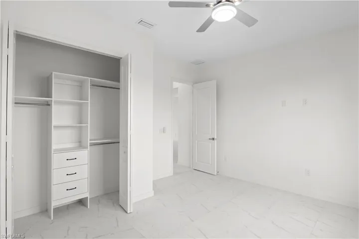 Unfurnished bedroom with light marble finish floors, a closet, and ceiling fan