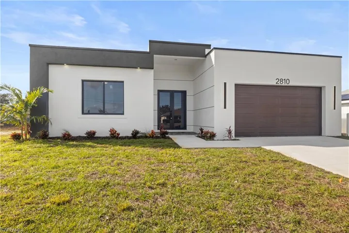 Modern home featuring a front lawn, stucco siding, driveway, and a garage