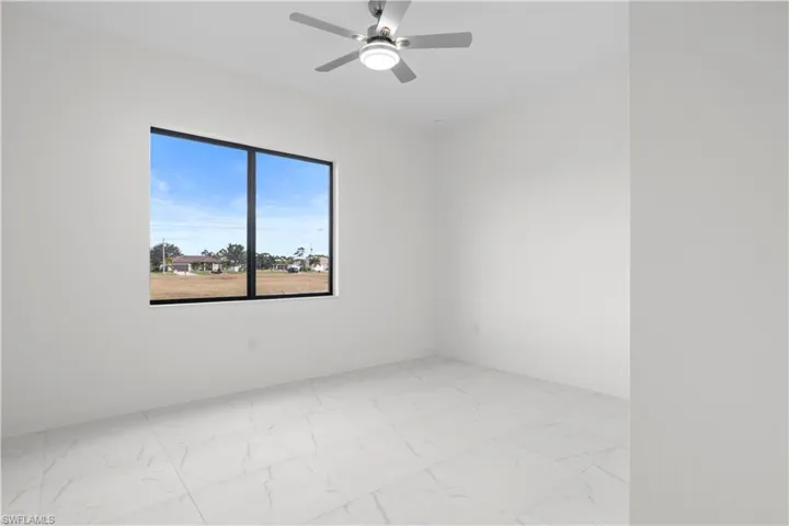 Empty room featuring light marble finish flooring and ceiling fan