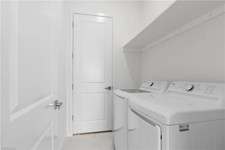 Laundry area with separate washer and dryer and light marble finish floors