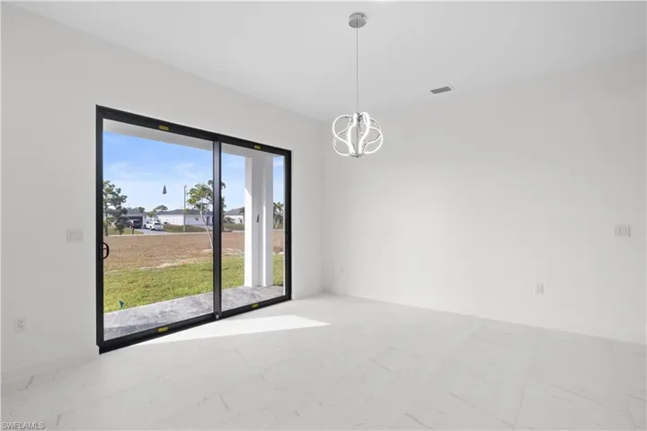 Empty room with light marble finish floors and a chandelier