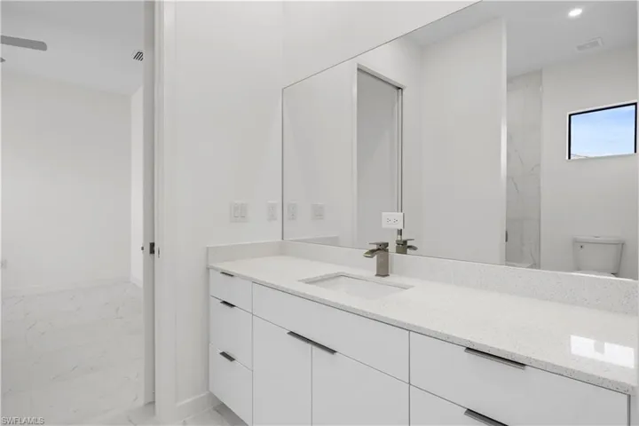 Full bath with light marble finish floors, vanity, and recessed lighting