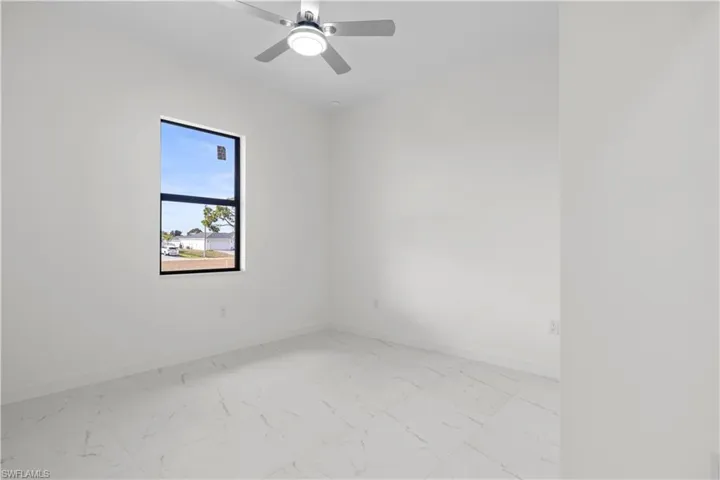 Unfurnished room featuring light marble finish flooring and a ceiling fan