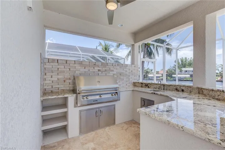 View of patio / terrace with a lanai, a sunroom, ceiling fan, and exterior kitchen
