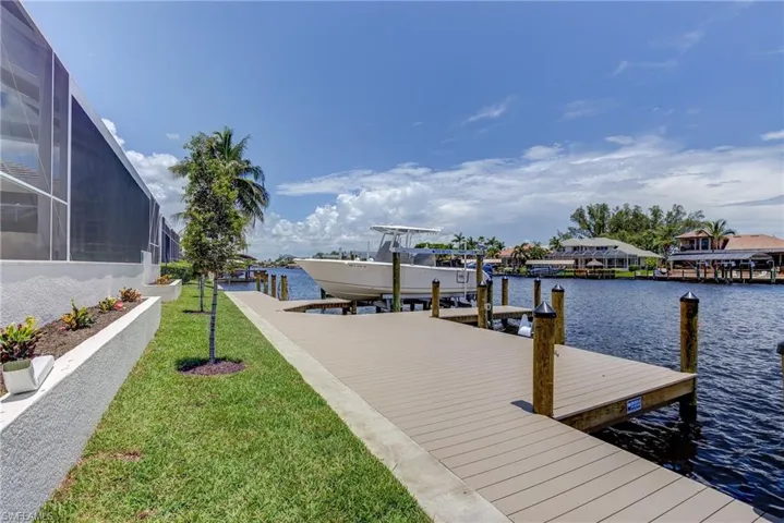Dock area featuring boat lift, a lawn, glass enclosure, a water view, and a sunroom