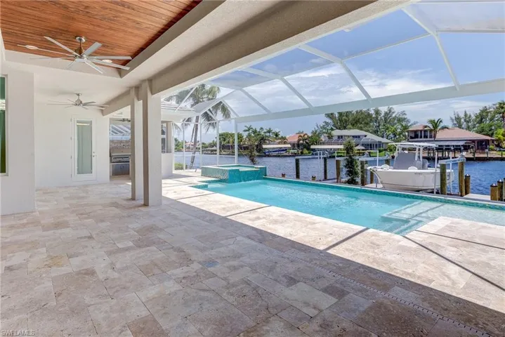 View of swimming pool with a patio, a lanai, boat lift, a dock, and a pool with connected hot tub