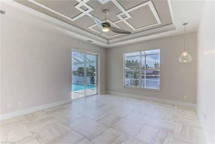 Empty room featuring a water view, ceiling fan, a tray ceiling, and healthy amount of natural light