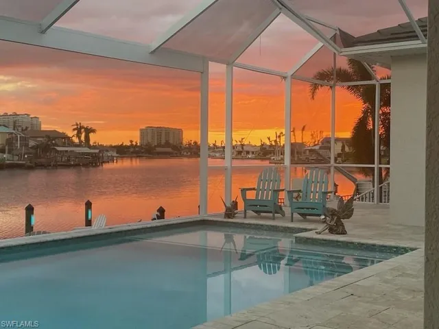 Pool at dusk featuring glass enclosure, an outdoor pool, and a sunroom