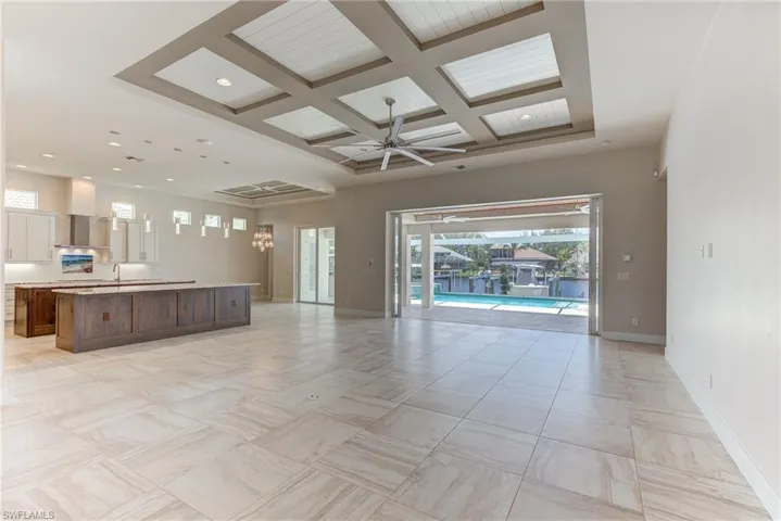 Unfurnished living room featuring coffered ceiling, a ceiling fan, healthy amount of natural light, beam ceiling, and recessed lighting