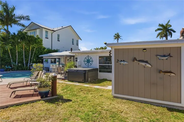 View of green lawn featuring a patio, an outdoor pool, a hot tub, and a wooden deck