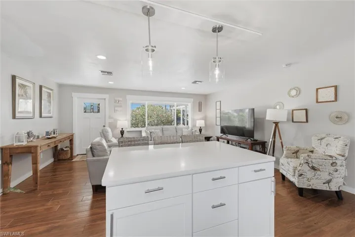 Kitchen with white cabinets, open floor plan, dark wood finished floors, decorative light fixtures, and light countertops