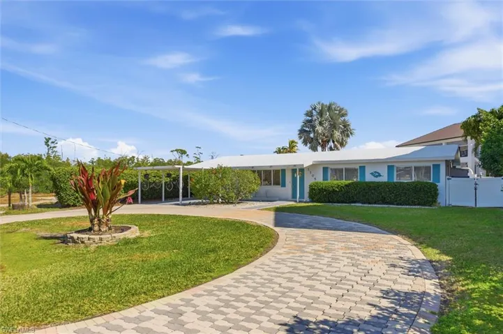 Single story home with curved driveway, stucco siding, a front lawn, and a gate