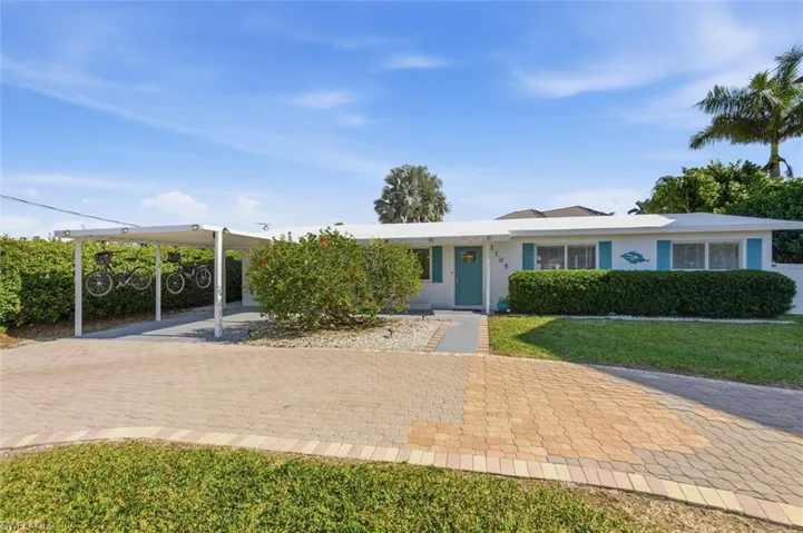 Ranch-style house with stucco siding, a carport, a front lawn, and driveway