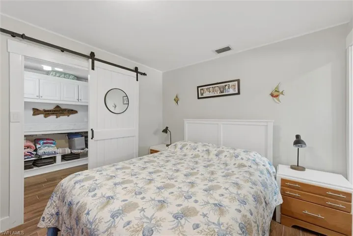 Bedroom with a barn door, wood finished floors, and crown molding