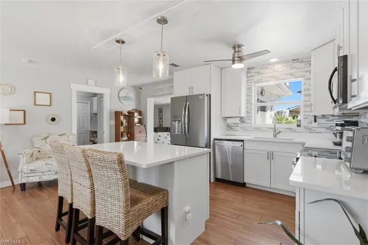 Kitchen featuring a kitchen breakfast bar, white cabinetry, stainless steel appliances, and light wood-style floors