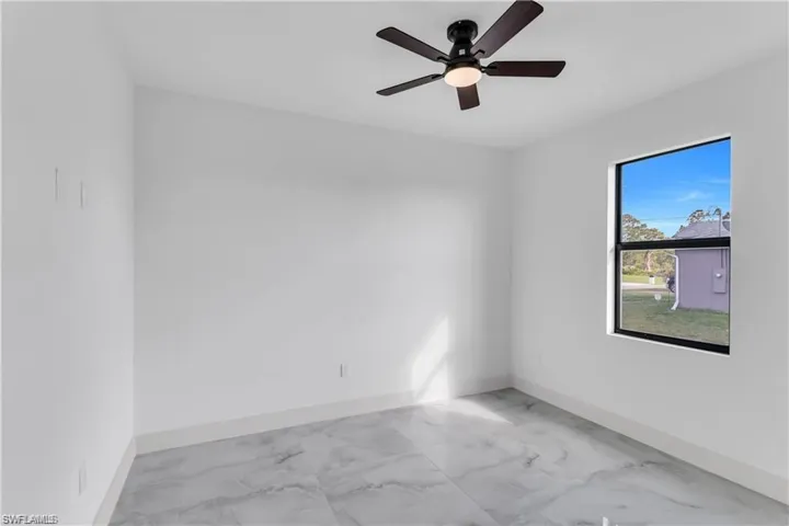 Unfurnished room with ceiling fan, marble finish floor, and baseboards