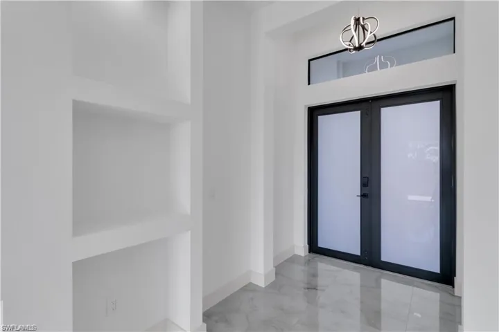 Foyer with french doors, baseboards, marble finish floor, and an inviting chandelier