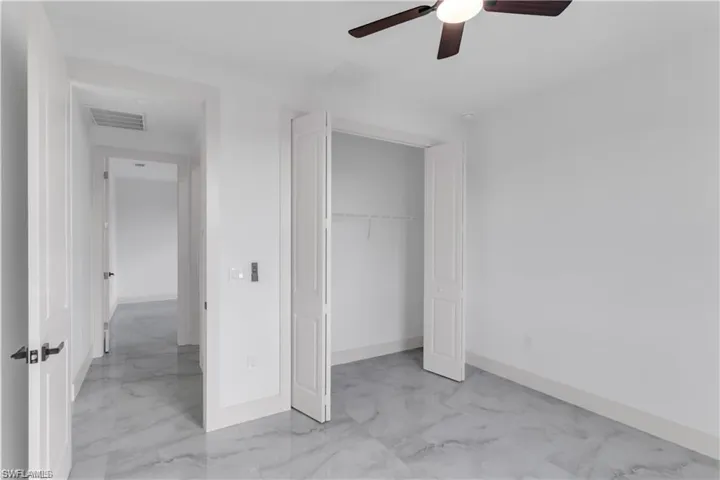 Unfurnished bedroom with a closet, visible vents, marble finish floor, and baseboards