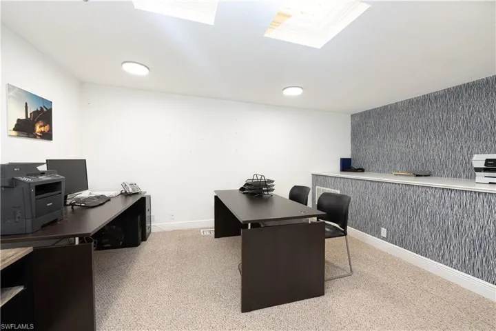 Office with a skylight, carpet, baseboards, and wallpapered walls