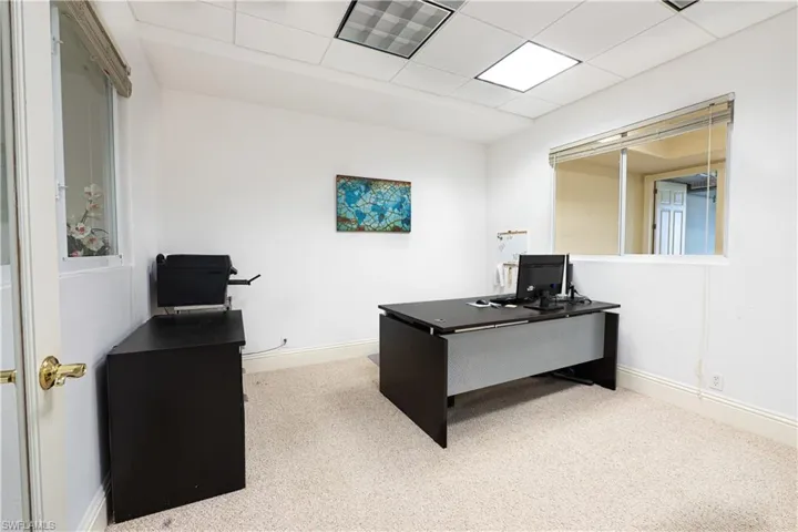 Office area featuring carpet flooring, baseboards, a drop ceiling, and visible vents