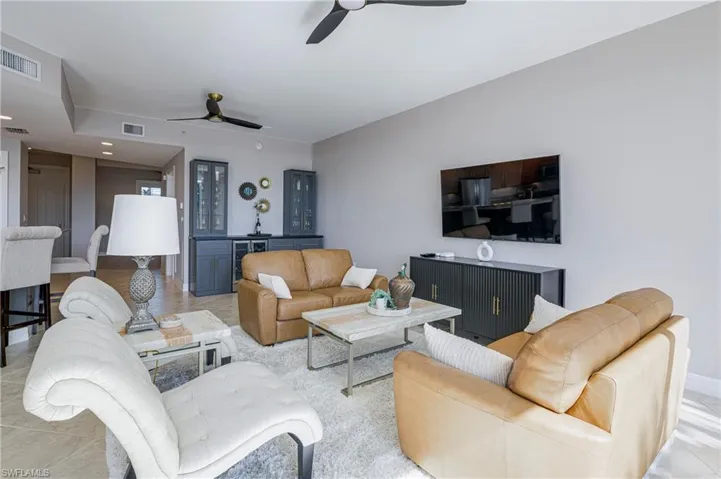 Spacious living area featuring light-toned walls, recessed lighting, and tile flooring