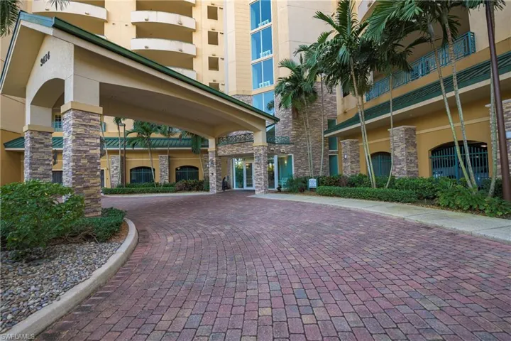 Expansive paver driveway leading to a covered porte-cochere entrance