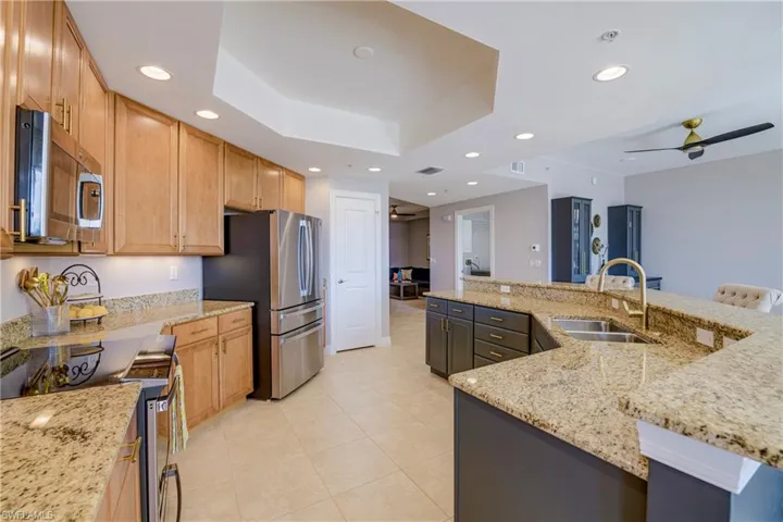 Kitchen featuring light-tone wood cabinetry, stainless steel appliances, and granite countertops