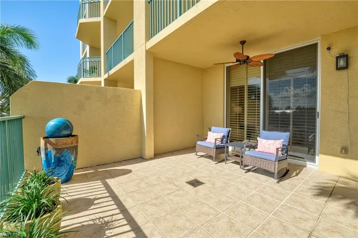 Spacious outdoor patio featuring neutral-toned tile flooring, a built-in ceiling fan, and sliding glass door access