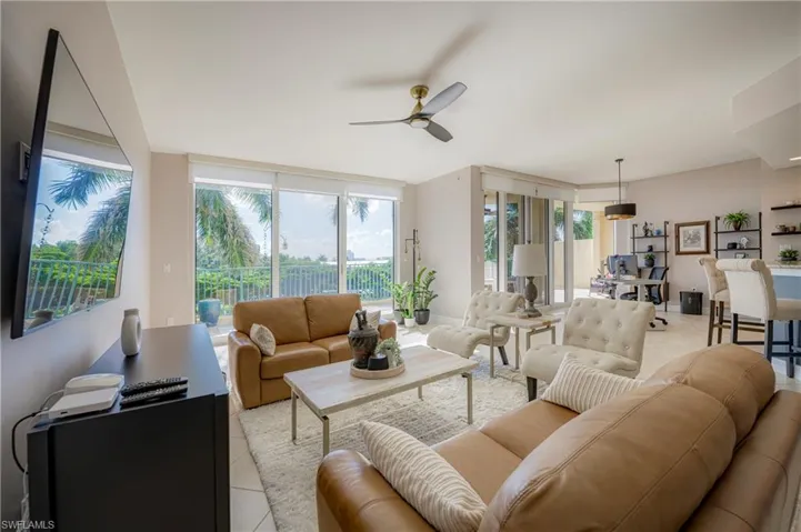 Spacious living area featuring large sliding glass doors, a ceiling fan, tiled flooring, and an open-concept design