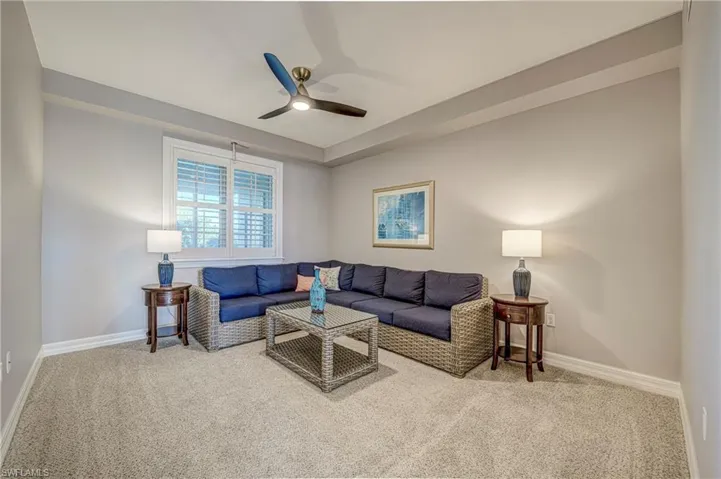 Carpeted room featuring a ceiling fan with integrated lighting, a window with plantation shutters, light gray walls, and white baseboards