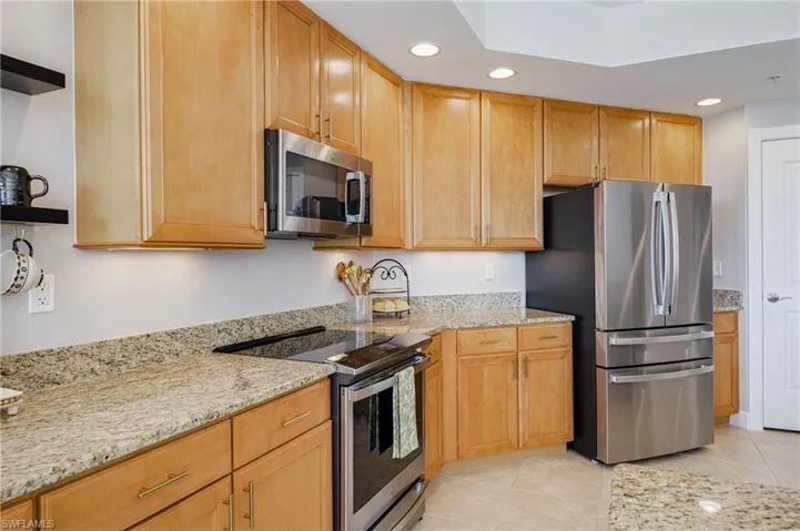 Kitchen featuring light wood cabinetry with gold-tone hardware, granite countertops, and recessed lighting