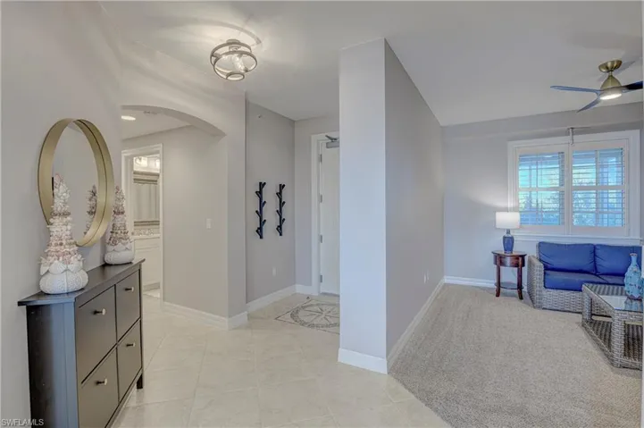 Travertine tile flooring in the entry hall featuring an arched doorway and a flush mount light fixture
