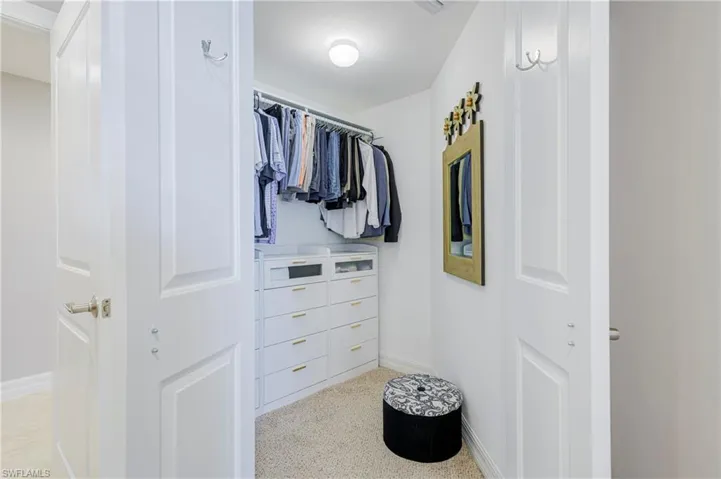 Walk-in closet featuring built-in custom cabinetry, integrated shelving, clothing rods, and textured carpeting