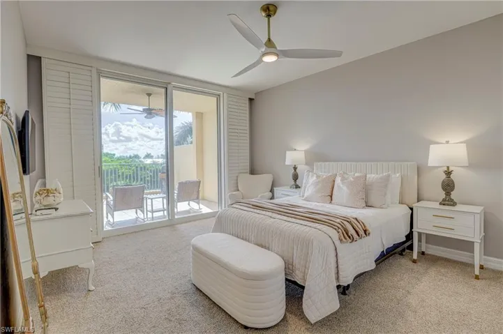 Room featuring light-toned carpeting, a built-in ceiling fan with integrated lighting, and a private balcony accessible via sliding glass doors